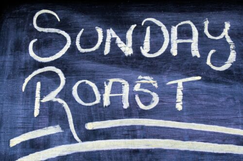 The wording text of Sunday Roast on a chalkboard. Concept photo of food and drinks.